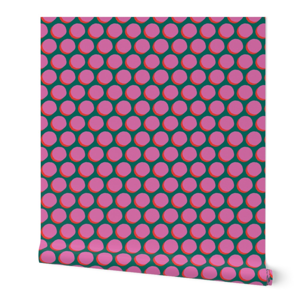 A roll of peel-and-stick wallpaper unraveled. The wallpaper has pink dots and a 3D effect from a subtle red shadow behind the dots, all over a green background.