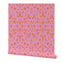 A roll of abstract wallpaper featuring a geometric pattern with orange shapes on a pink background.