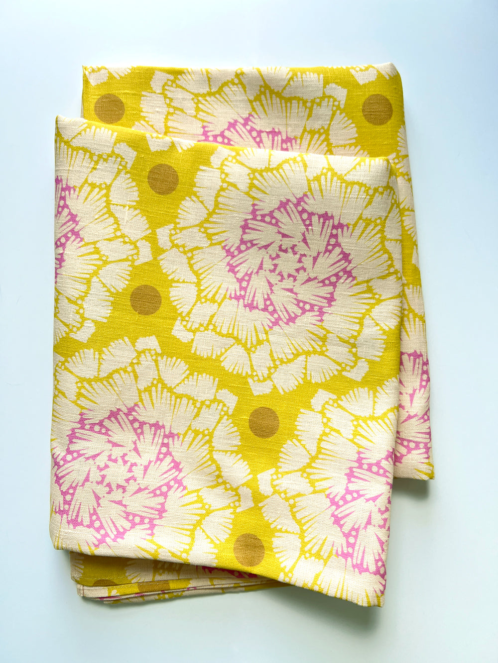 Bright yellow and pink patterned tablecloth on a white background