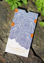 Art calendar with abstract floral design by Leila Simon Hayes on a stone surface with greenery