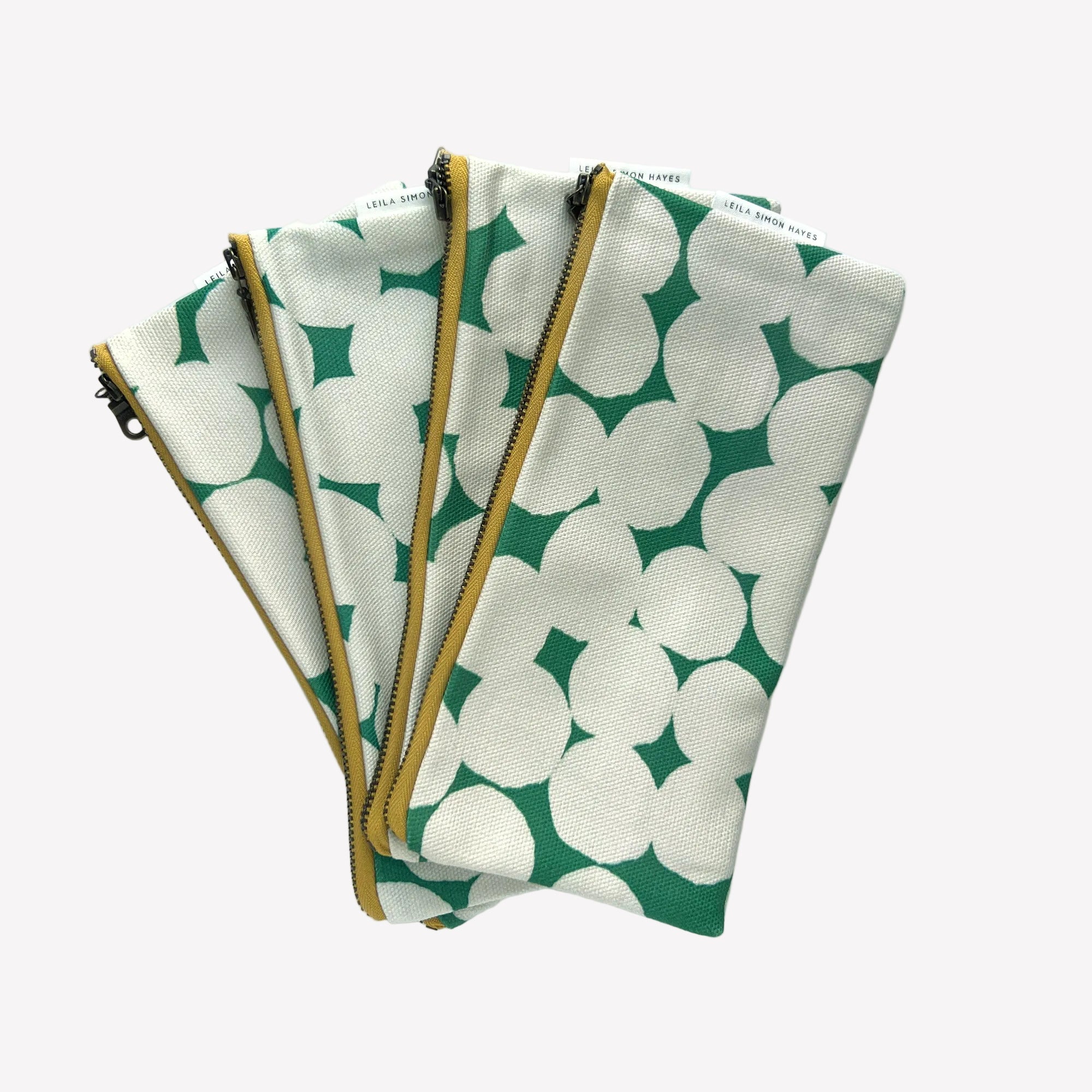 Four green and white patterned pouches with gold zippers on a white background