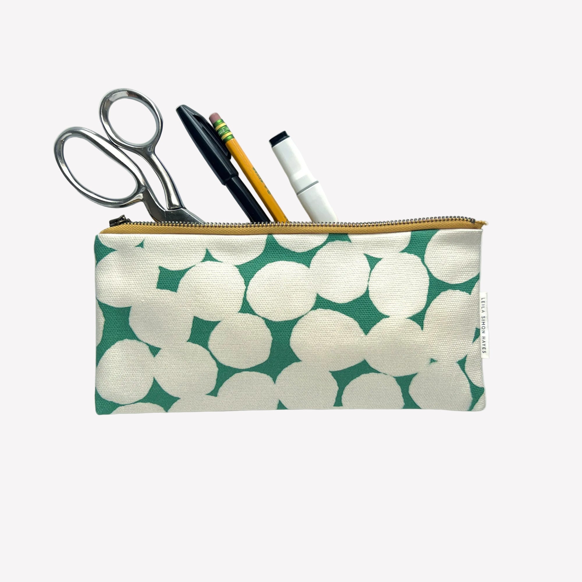Pencil case with green and white pattern containing scissors, pens, and a marker on a light gray background