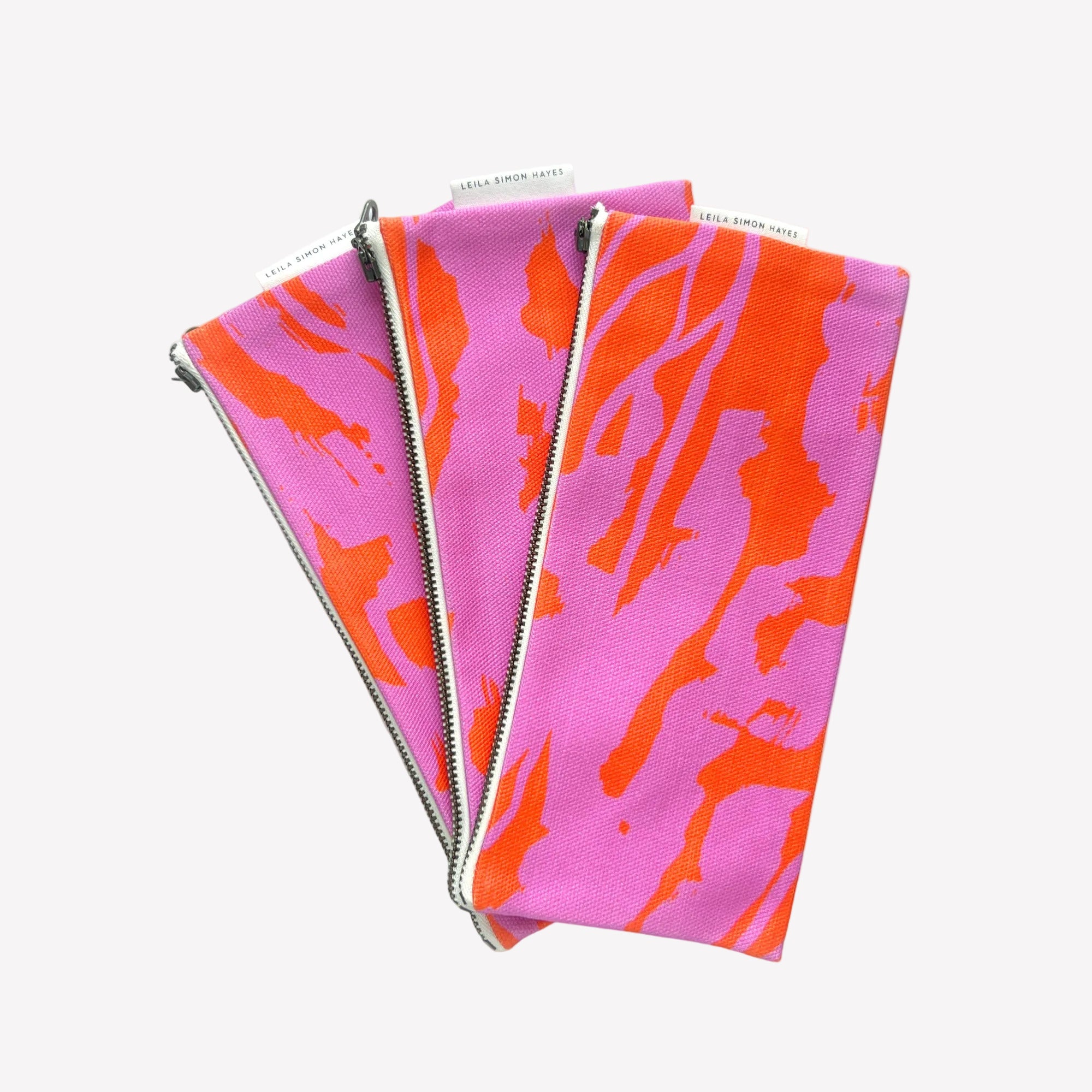 Three Pink and orange wavy design pencil cases fanned out