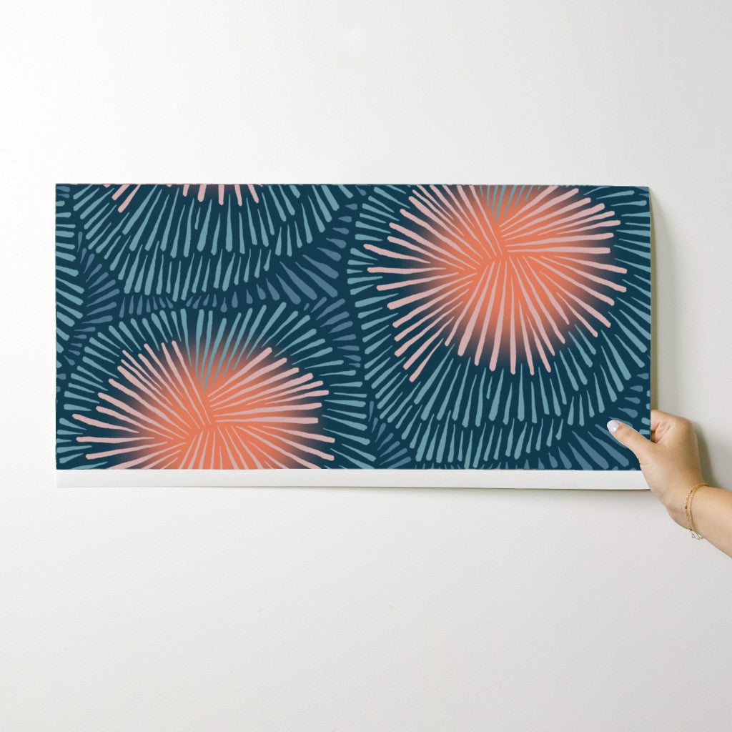 Hand holding a wallpaper swatch with a blue and pink abstract pattern on a white background. Designed by artist Leila Simon Hayes.