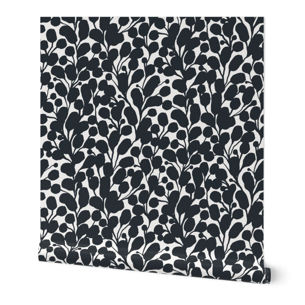 A roll of wallpaper featuring a hand-painted botanical leaf pattern in black and a white base. Designed by artist Leila Simon Hayes.