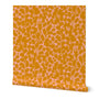 A roll of wallpaper featuring a hand-painted botanical leaf pattern with orange and pink hues. Designed by artist Leila Simon Hayes.