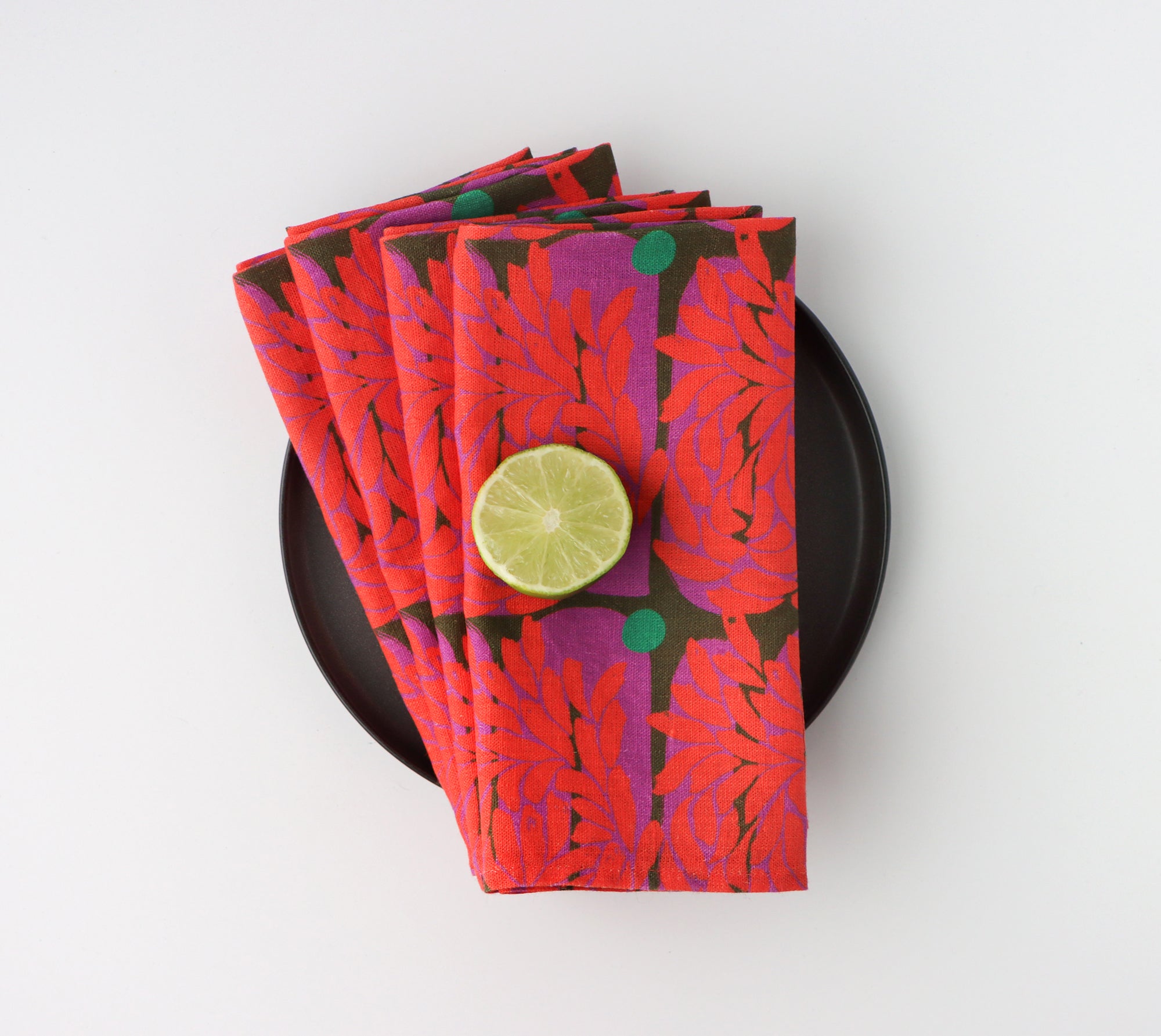 Set of four red dinner napkins with a vibrant floral pattern, designed by artist Leila Simon Hayes. 