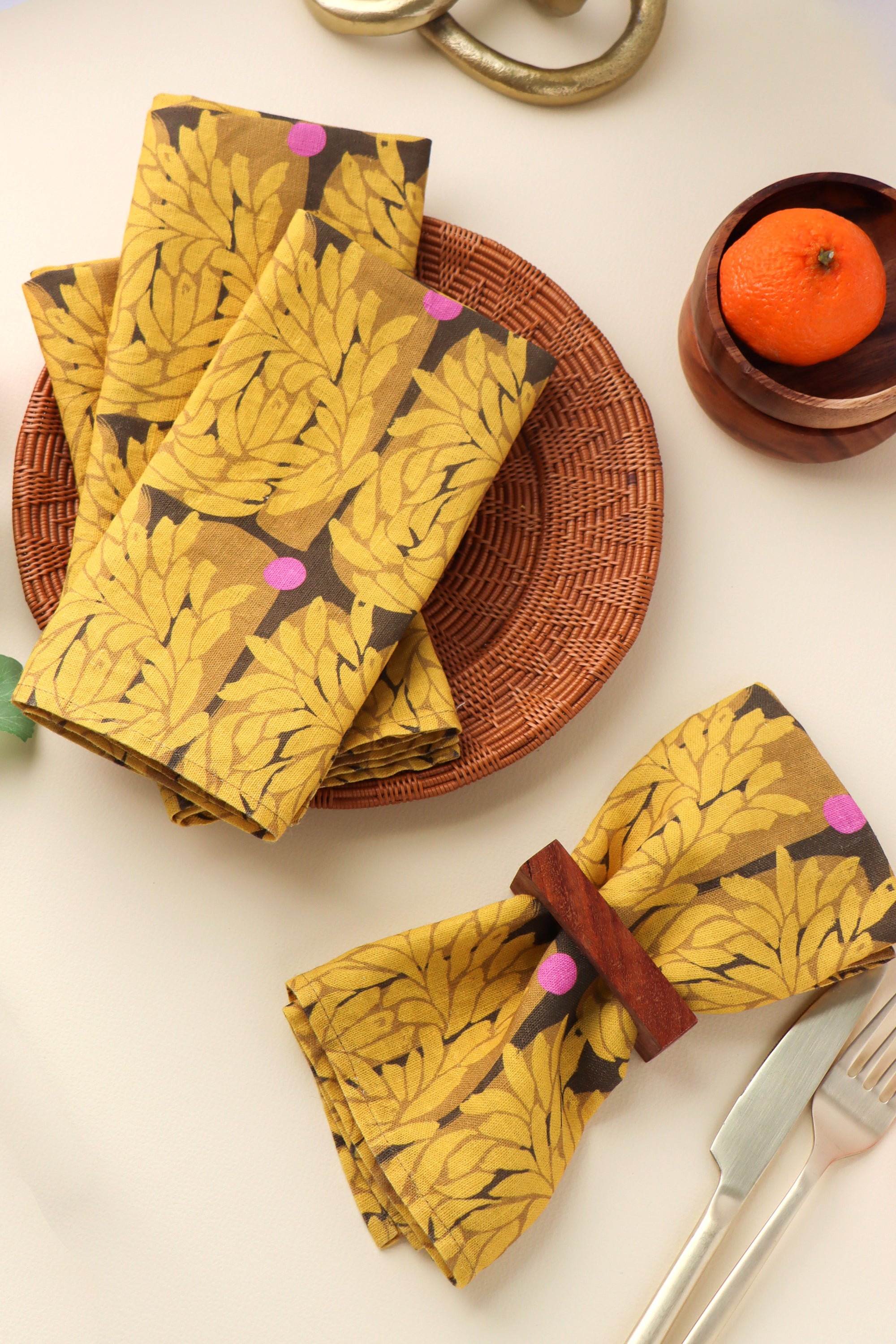 Yellow patterned napkins on a table with a wicker basket and orange fruit. Designed by artist Leila Simon Hayes.