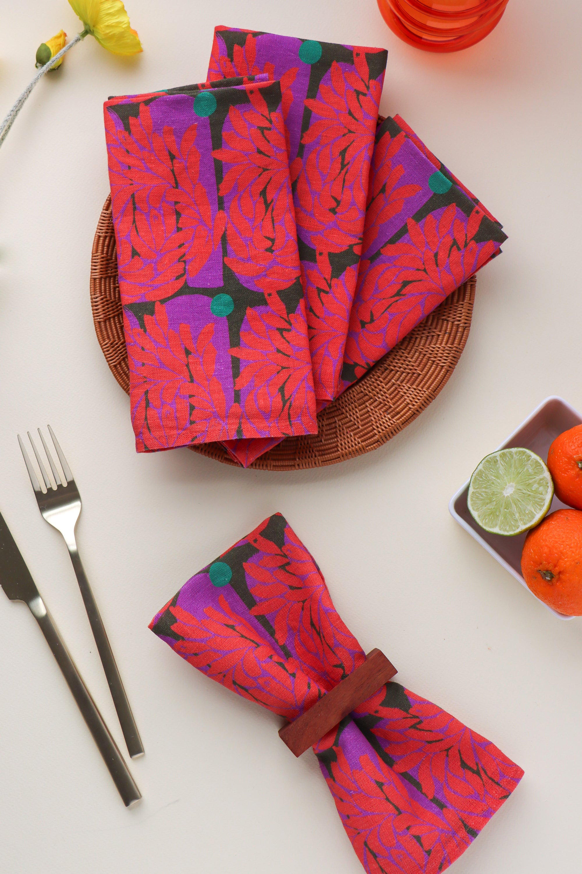Set of four, folded red dinner napkins with a vibrant floral pattern, designed by artist Leila Simon Hayes. 