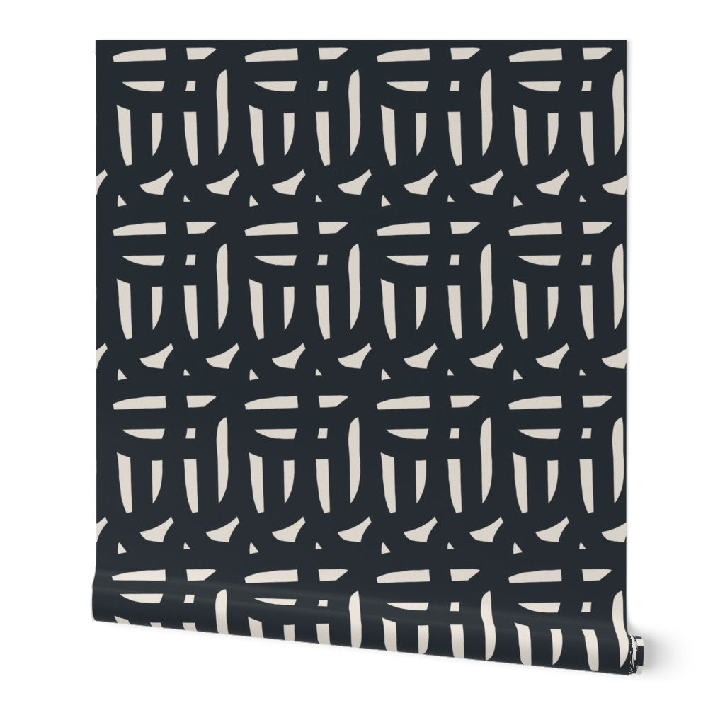 A roll of peel-and-stick, removable wallpaper featuring a geometric pattern with black and white colors. Designed by artist Leila Simon Hayes.
