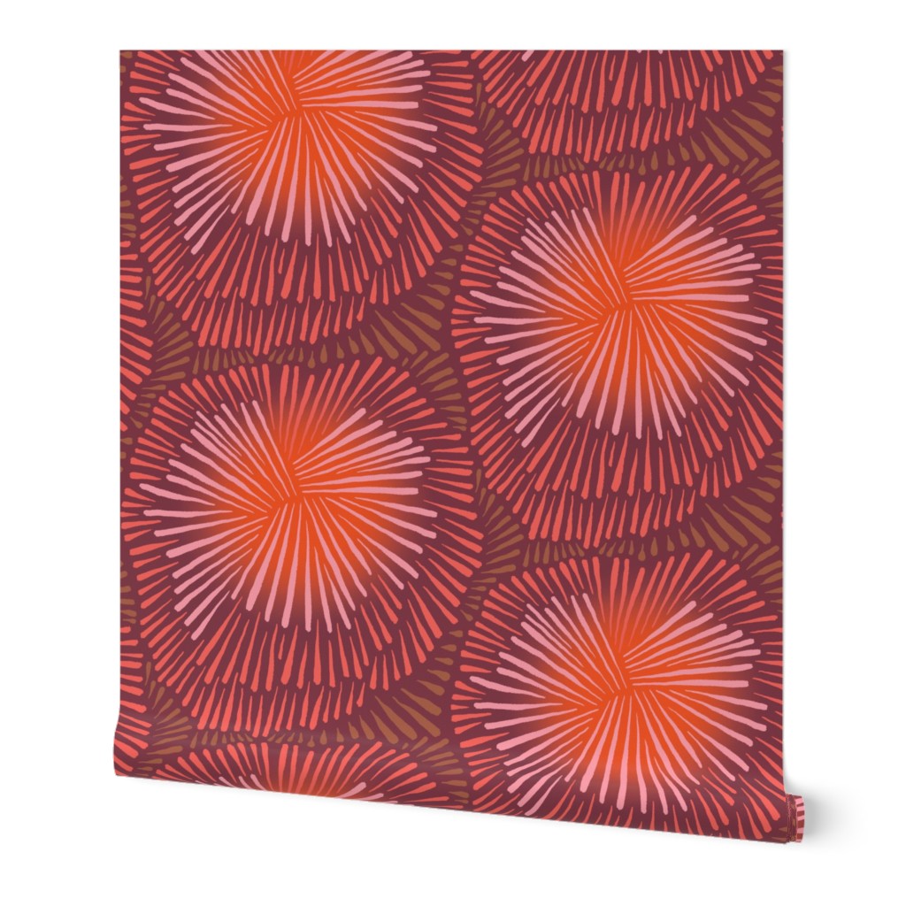 A roll of peel-and-stick wallpaper unraveled, with a white background. The abstract wallpaper design has large pink and red firework floral designs. Designed by artist Leila Simon Hayes.