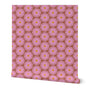 A roll of wallpaper featuring a repeating pattern of pink flowers with yellow centers on a brown background. Designed by artist Leila Simon Hayes.