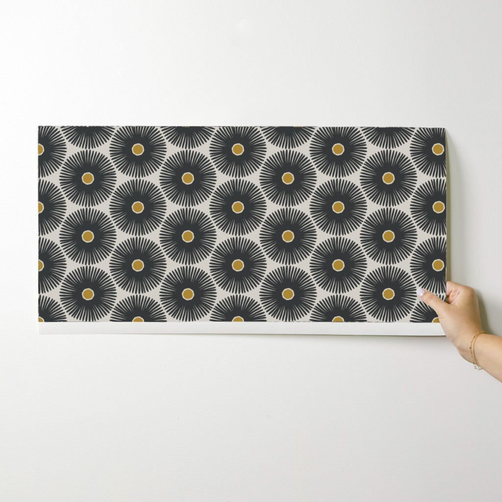 Person holding a decorative wallpaper swatch with geometric pattern on a white background. Designed by artist Leila Simon Hayes.