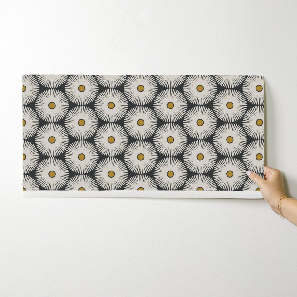 Person holding a wallpaper swatch with a floral pattern on a white surface. Designed by artist Leila Simon Hayes.