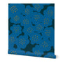 A roll of blue wallpaper with a hand-painted abstract floral design including larger blue flowers with yellow dotted centers, slightly overlapping. Designed by artist Leila Simon Hayes.