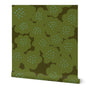 A roll of green wallpaper with a hand-painted abstract floral design including larger olive green flowers with blue dotted centers, slightly overlapping. Designed by artist Leila Simon Hayes.