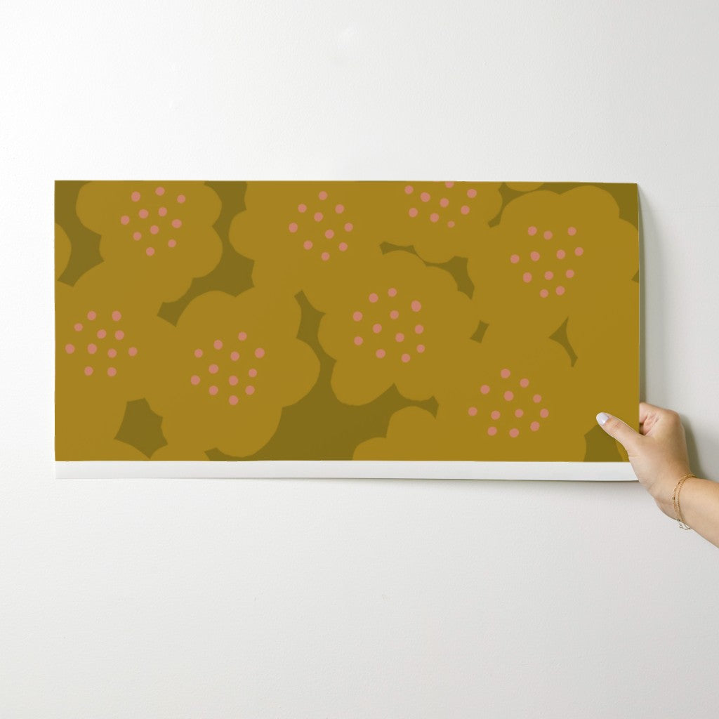 Hand holding a rectangular wallpaper swatch with a floral pattern on a white background. Designed by artist Leila Simon Hayes.