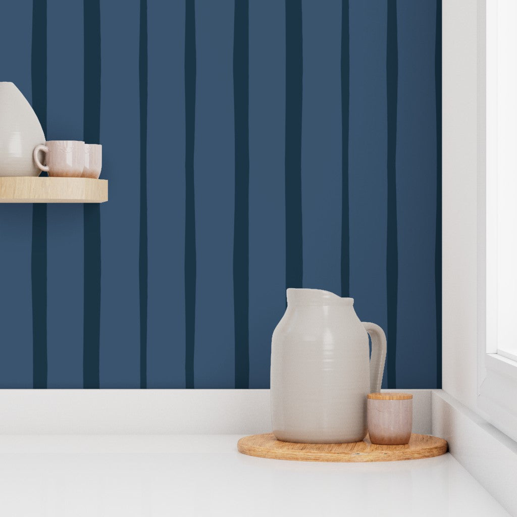 White ceramic pitcher and cups on a wooden tray against a blue striped wall. Designed by artist Leila Simon Hayes.