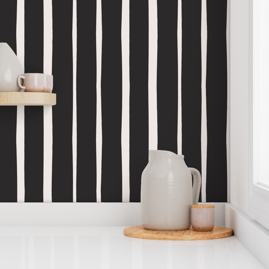 Ceramic pitcher and cups on a wooden tray against a black and white striped wall. Designed by artist Leila Simon Hayes.