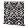 Roll of peel-and-stick wallpaper on a white background. The wallpaper is a black kaleidoscope, botanical, and floral pattern on a white base. Designed by artist Leila Simon Hayes.