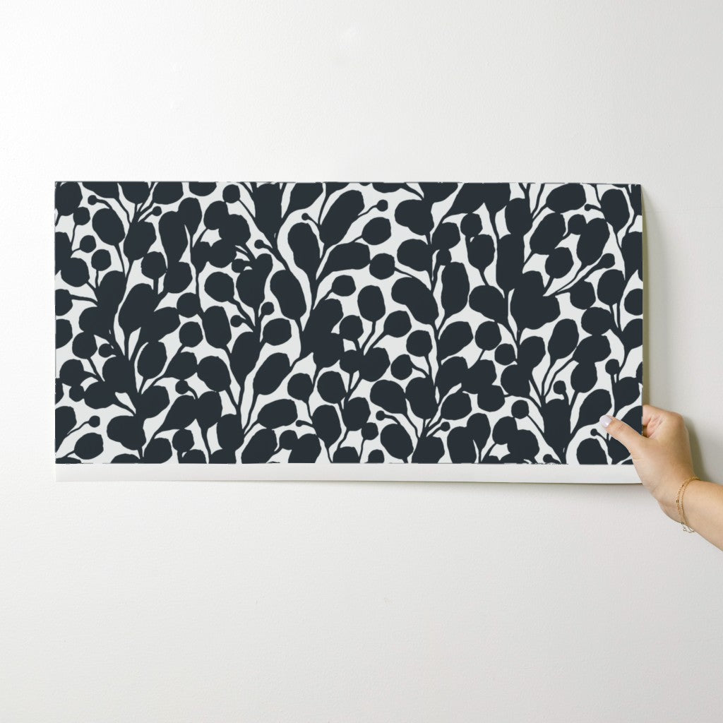 Hand holding a black and white patterned wallpaper swatch on a white background. Designed by artist Leila Simon Hayes.