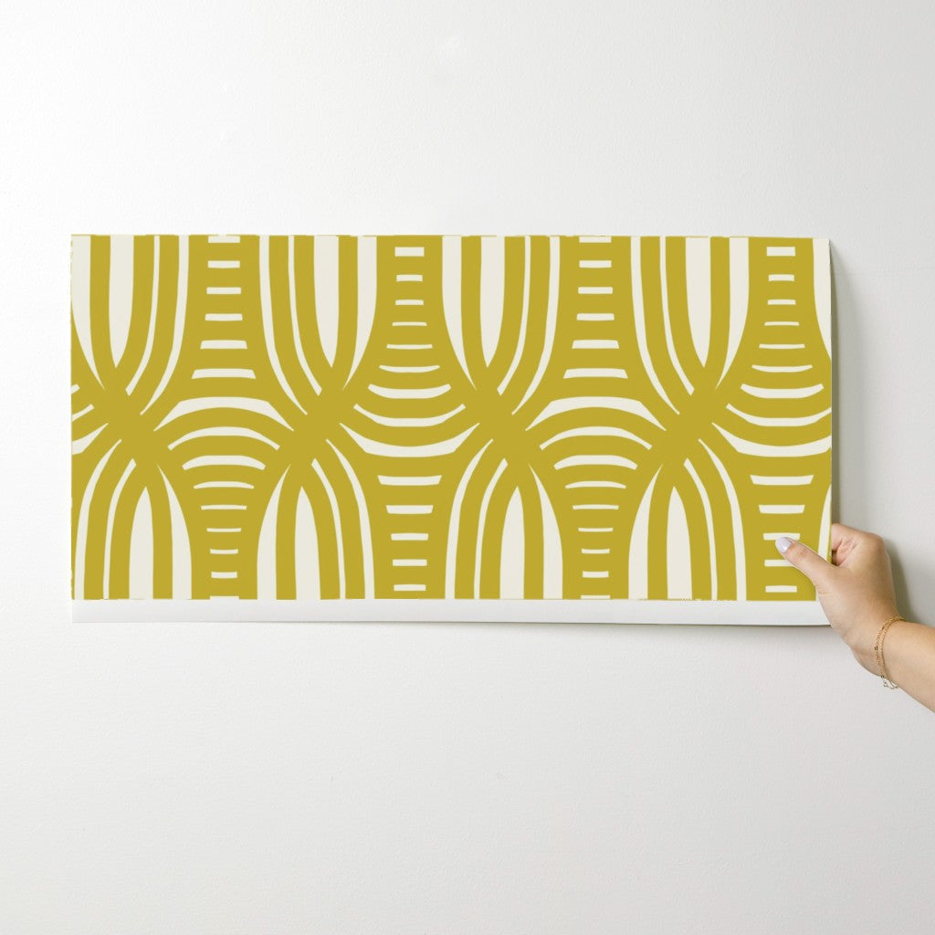 Hand holding a yellow and white patterned paper against a white background. Designed by artist Leila Simon Hayes.