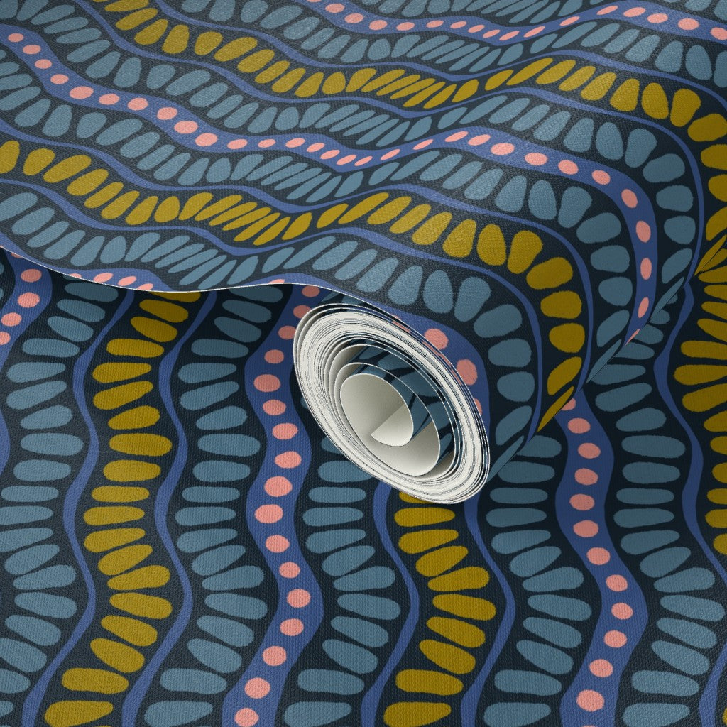 Close-up of a roll of wallpaper with a colorful pattern, featuring blue, yellow, and pink colors. Designed by artist Leila Simon Hayes. 