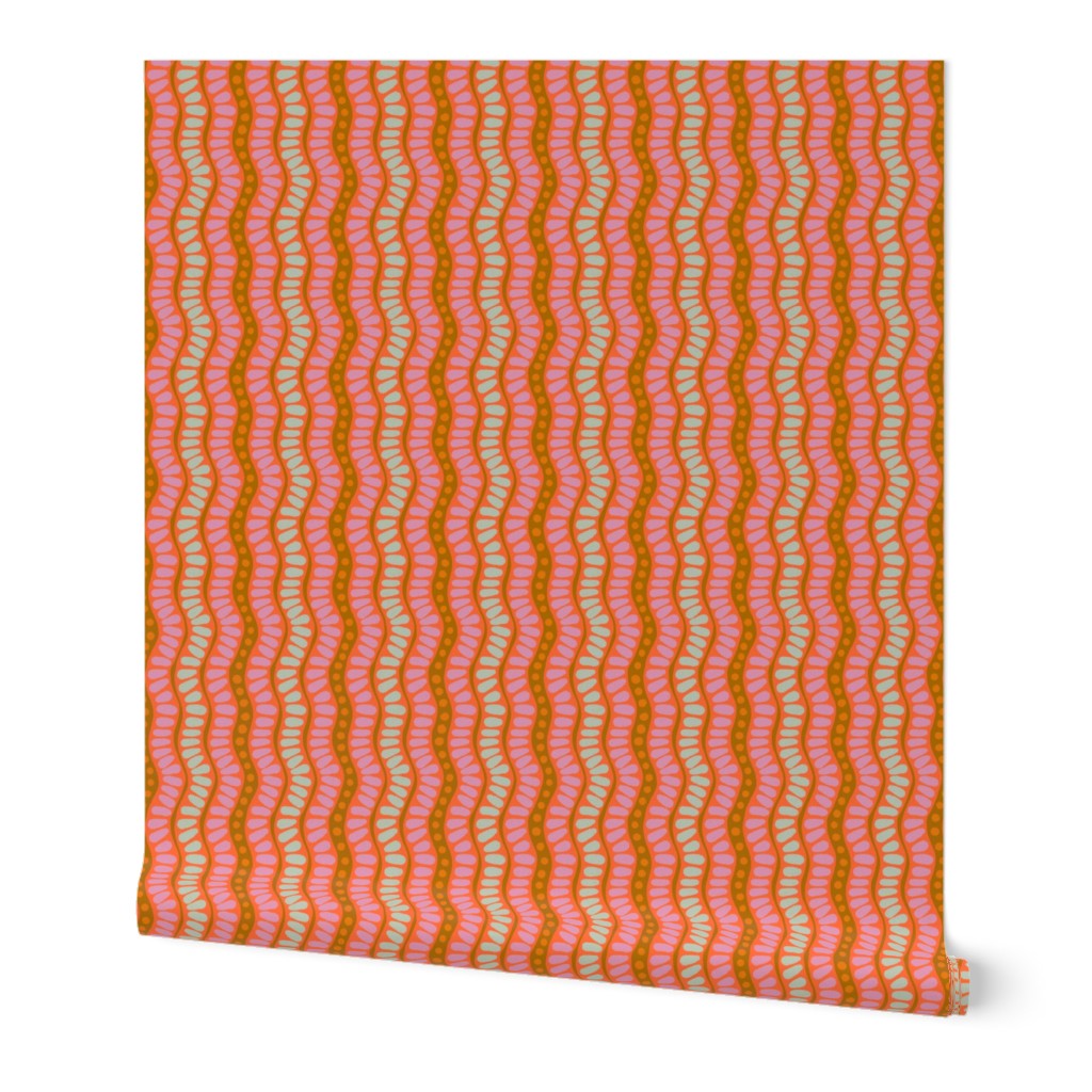 Roll of wallpaper over a white background. The wallpaper has a wavy pink and green pattern. Designed by artist Leila Simon Hayes. 
