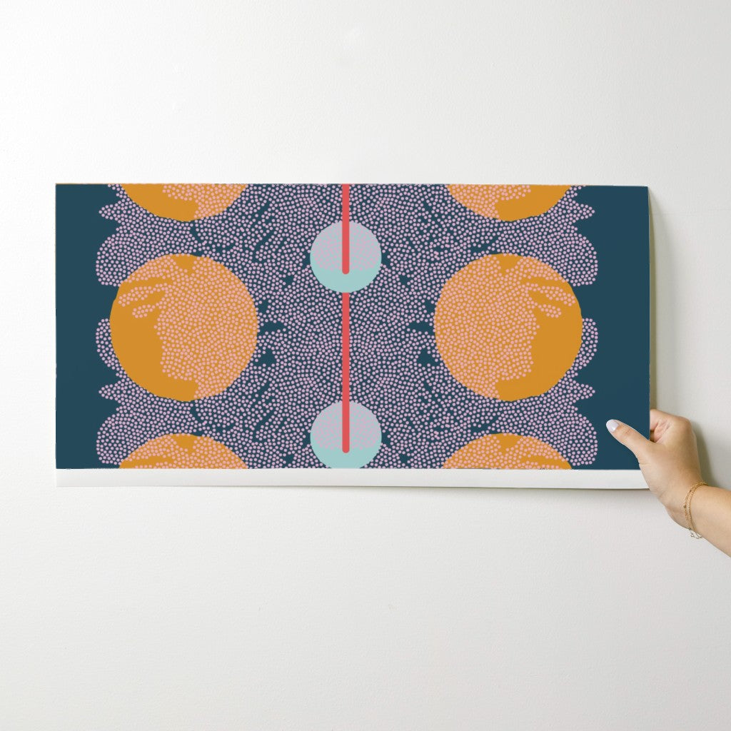 Hand holding a wallpaper swatch with a colorful abstract design on a white background. Designed by artist Leila Simon Hayes.