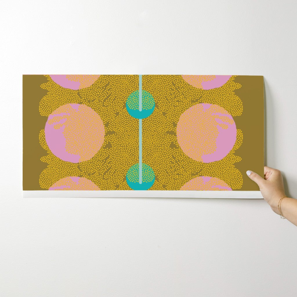 Hand holding a wallpaper swatch with a colorful abstract design on a white background. Designed by artist Leila Simon Hayes.