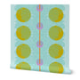 A roll of peel-and-stick wallpaper unraveled, on a white background. The abstract wallpaper design has yellow and pink circles, blue dots, and a red stripe down the middle, on a light blue base. Designed by artist Leila Simon Hayes.