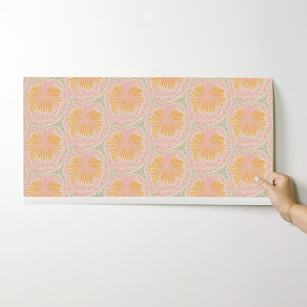Hand holding a wallpaper swatch with a floral pattern on a white background. Designed by artist Leila Simon Hayes.