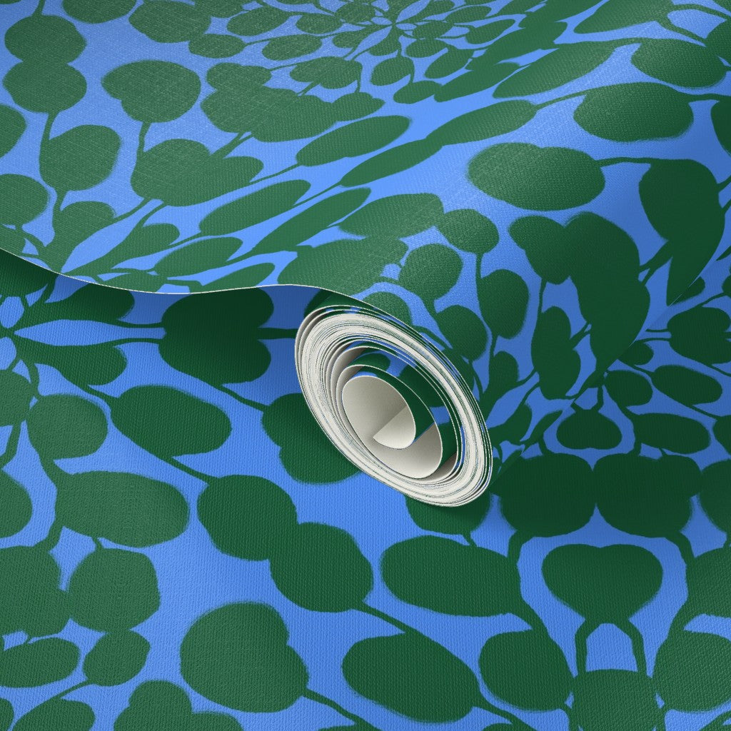 Roll of green leaf patterned paper on a blue background. Designed by artist Leila Simon Hayes.