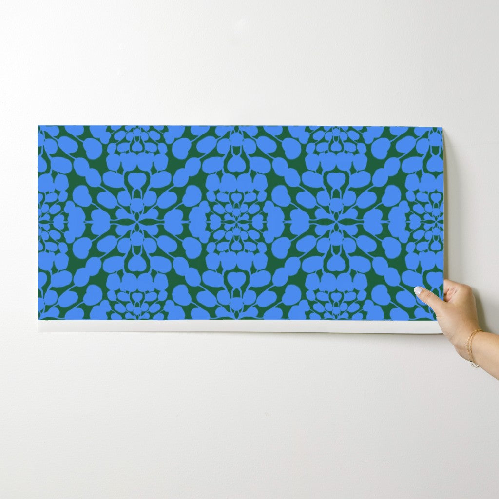 Hand holding a wallpaper swatch with blue abstract pattern on a green background. Designed by artist Leila Simon Hayes.
