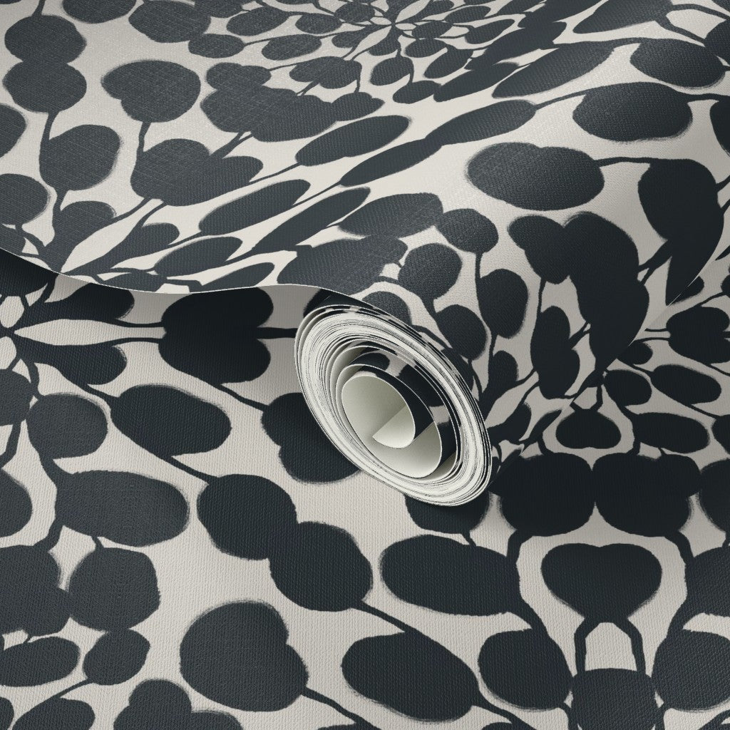 Roll of wallpaper with black leaf pattern on a white background. Designed by artist Leila Simon Hayes.