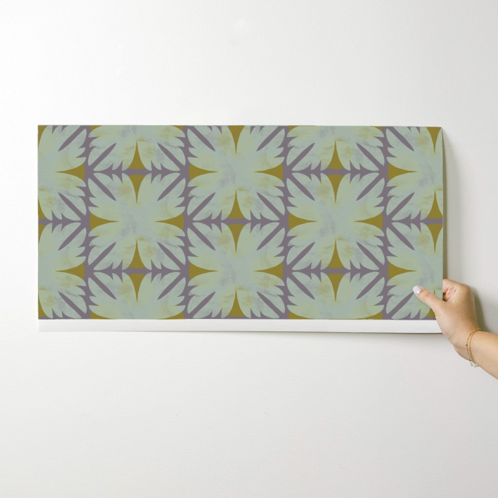 Hand holding a wallpaper swatch with a geometric pattern on a white background. Designed by artist Leila Simon Hayes 