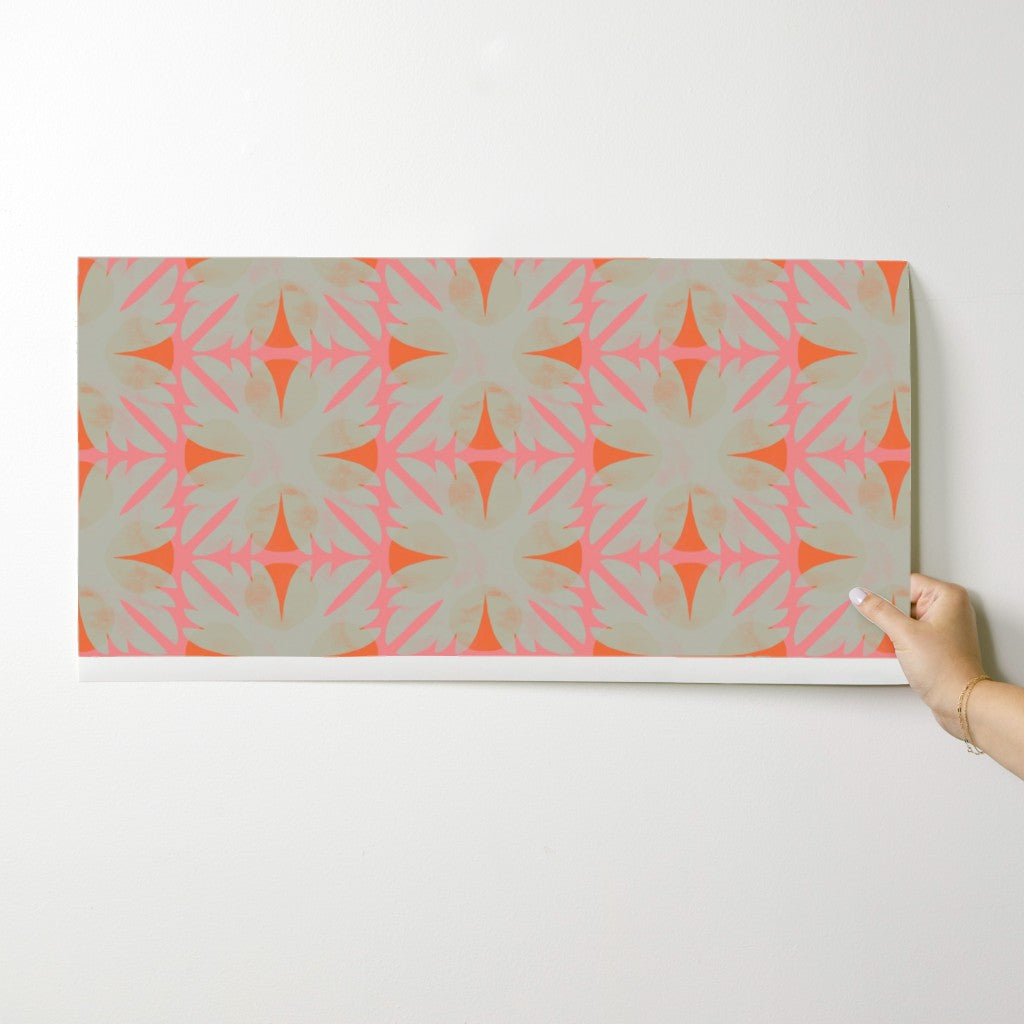 Hand holding a wallpaper swatch with a geometric pattern against a white background. Designed by artist Leila Simon Hayes.