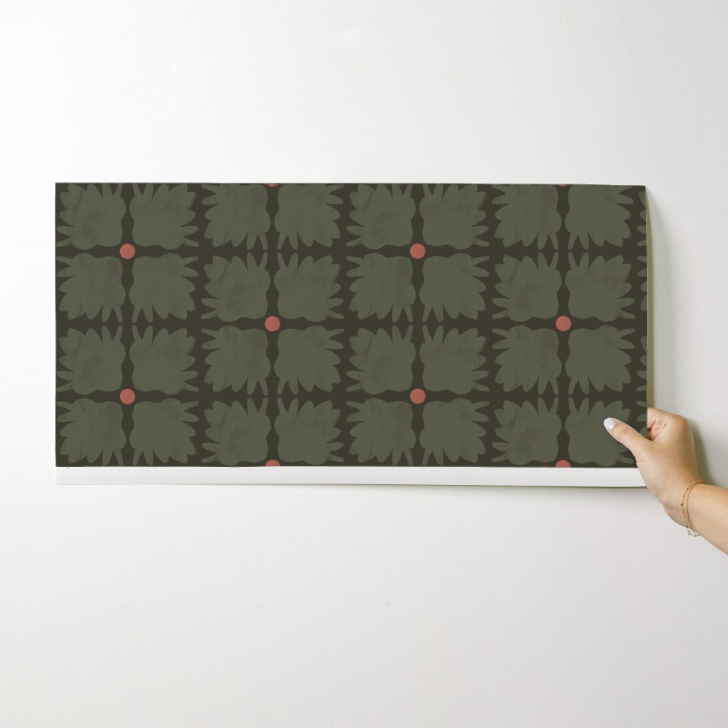 Hand holding a wallpaper swatch with a geometric pattern on a white background. Designed by artist Leila Simon Hayes.