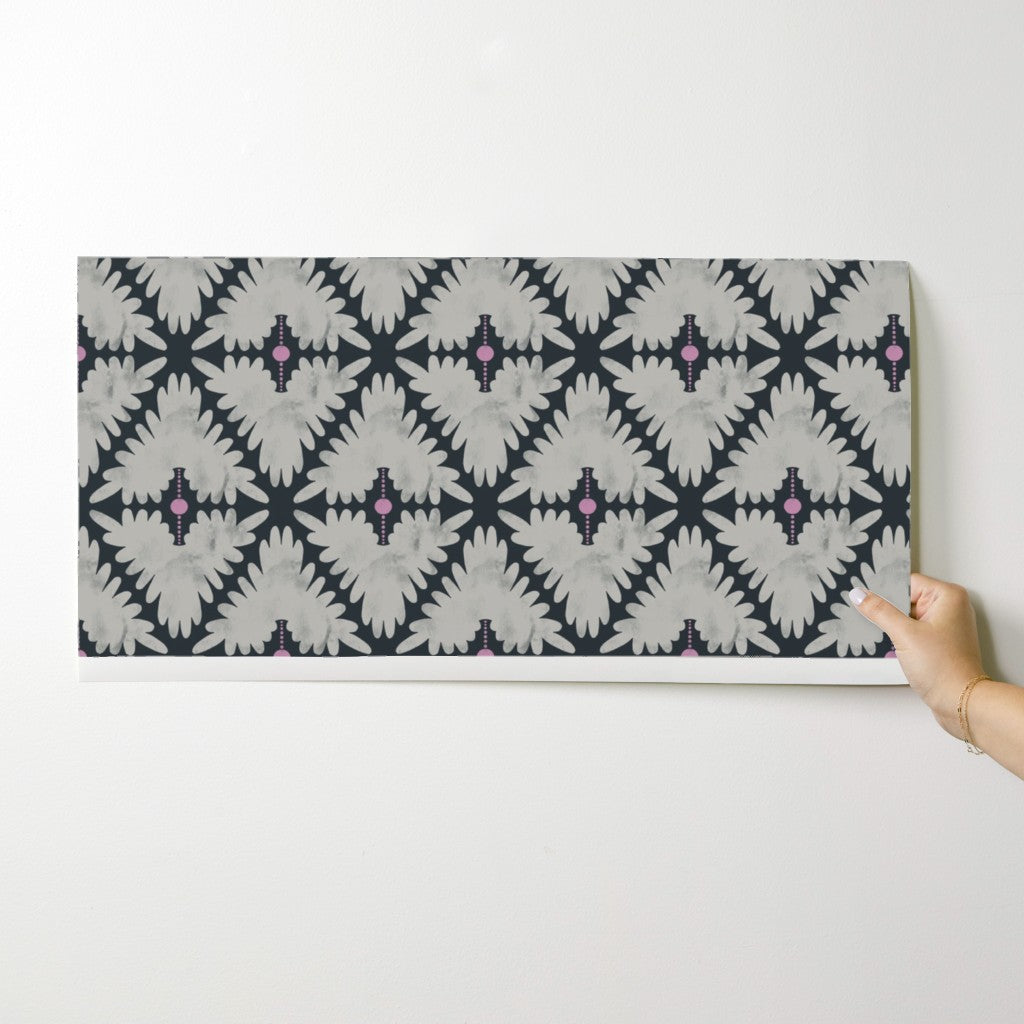 Person holding a wallpaper swatch with a geometric pattern on a white background. Designed by artist Leila Simon Hayes.