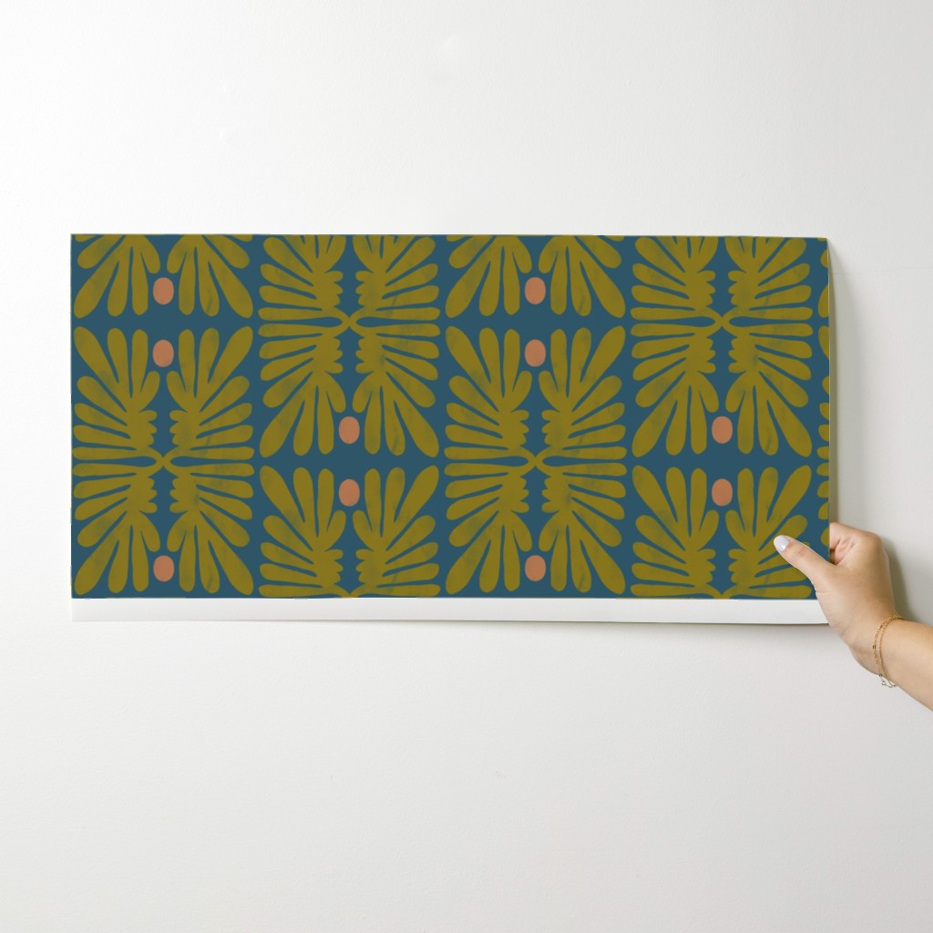 Hand holding a wallpaper swatch with a leaf floral pattern against a white background. Designed by artist Leila Simon Hayes. 