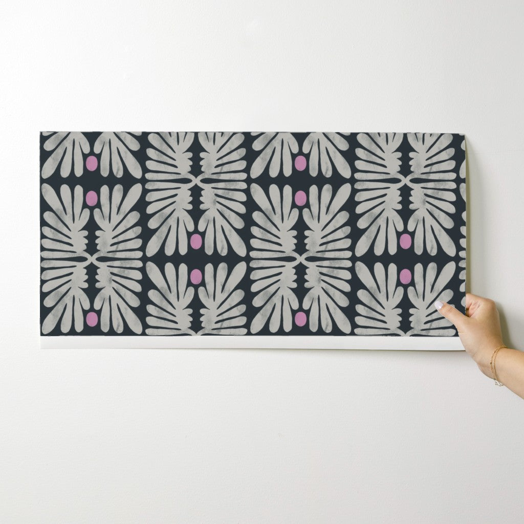 Person holding a wallpaper swatch with a geometric pattern on a white background. Designed by artist Leila Simon Hayes. 