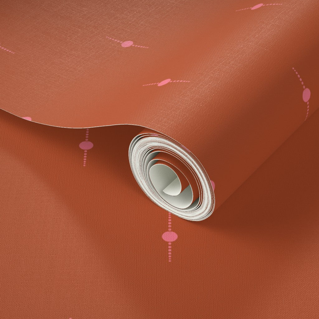 Roll of burnt orange wallpaper with an intricate pink geometric star pattern. Designed by artist Leila Simon Hayes. 