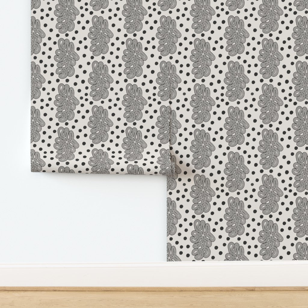 Dots and loops abstract patterned wallpaper with black and white design on a white background. Designed by artist Leila Simon Hayes. 