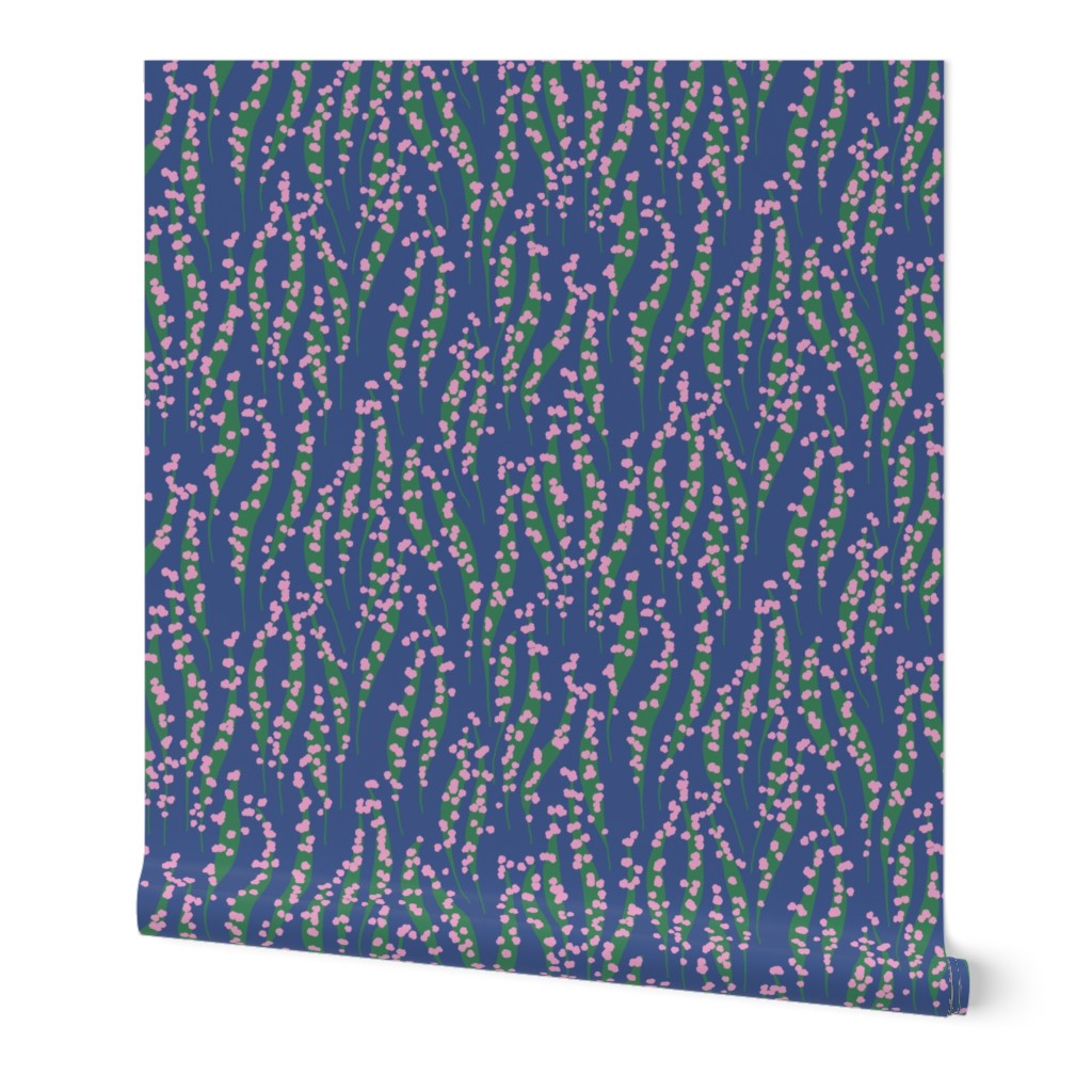 Roll of wallpaper with a blue background and pink and green pattern. Designed by Leila Simon Hayes. 