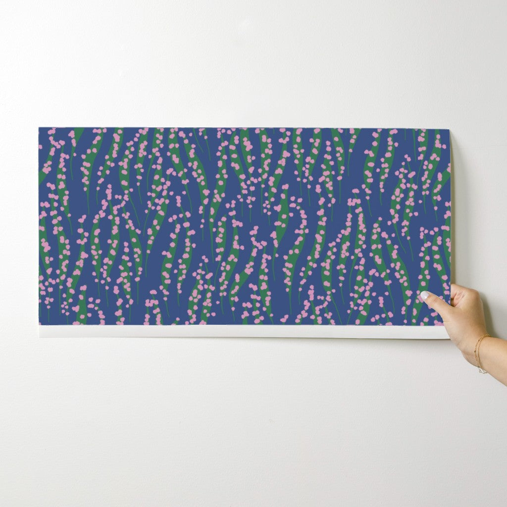 Hand holding a rectangular canvas with a floral pattern against a white background. Designed by Leila Simon Hayes. 