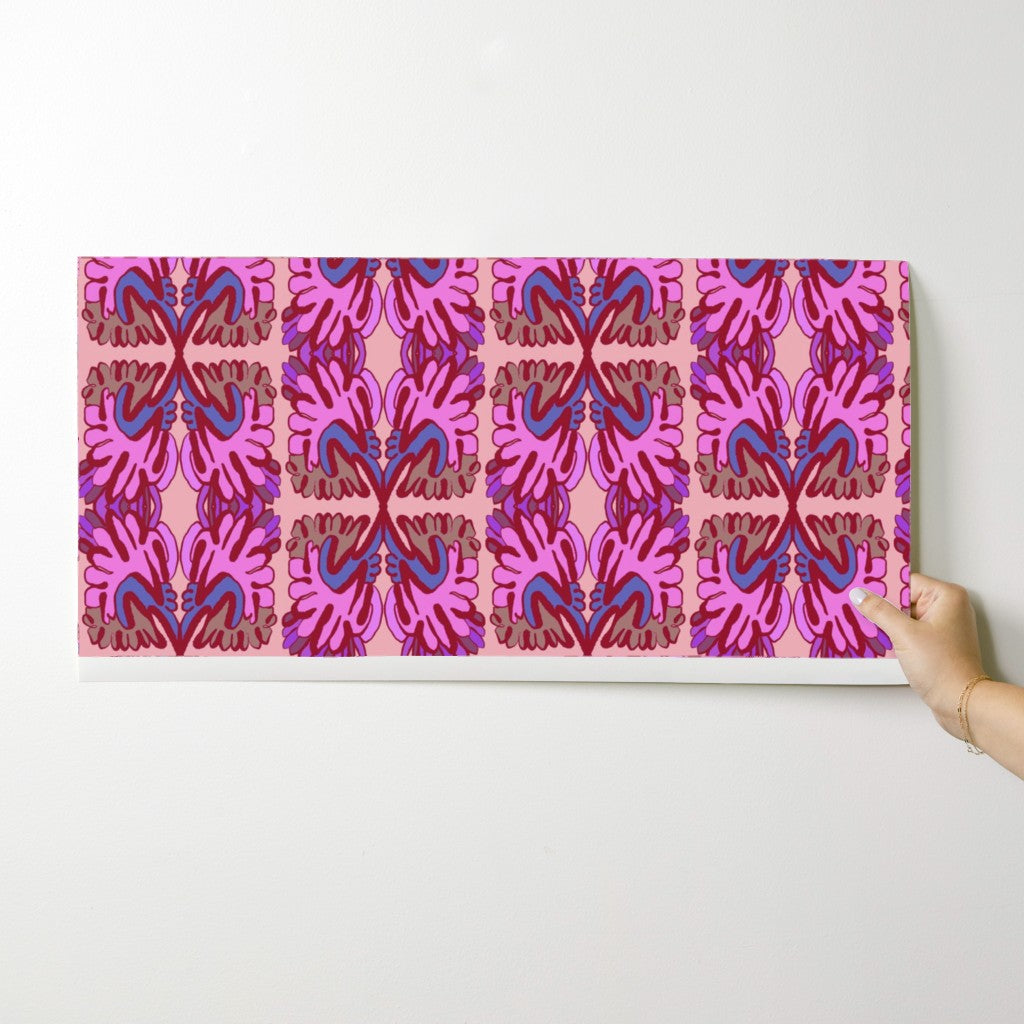 Person holding a pink and blue wallpaper swatch against a white background. Designed by artist Leila Simon Hayes.