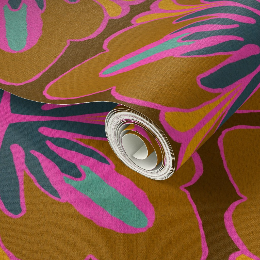 A close-up of a rolled sheet of patterned wallpaper or fabric with an abstract floral design in mustard brown, bright pink, teal, and dark navy, shown against the same patterned material. Designed by artist Leila Simon Hayes.