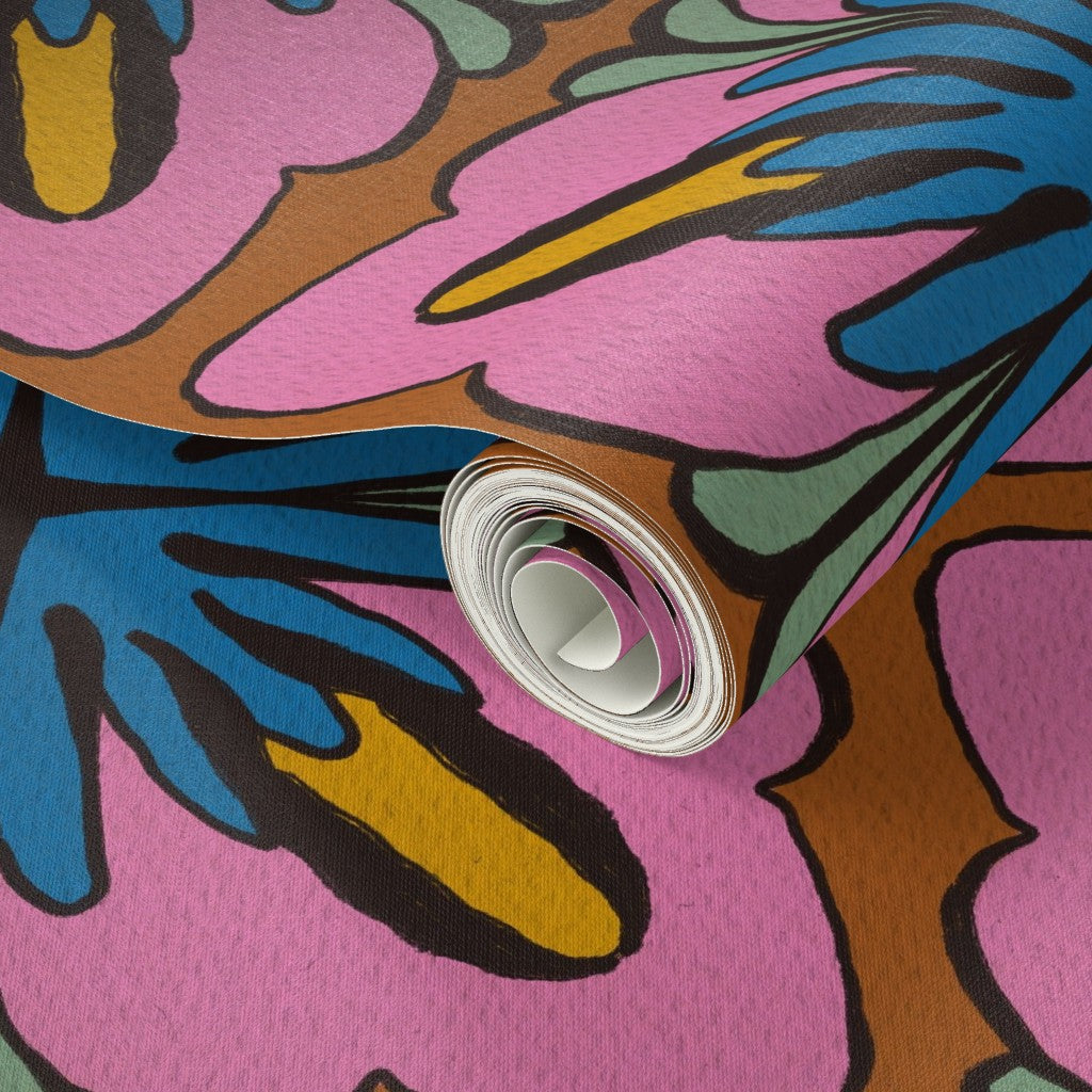 A close-up of a rolled sheet of patterned material, likely fabric or wallpaper, featuring a bold abstract floral design in pink, blue, yellow, brown, and green with black outlines. Designed by artist Leila Simon Hayes.