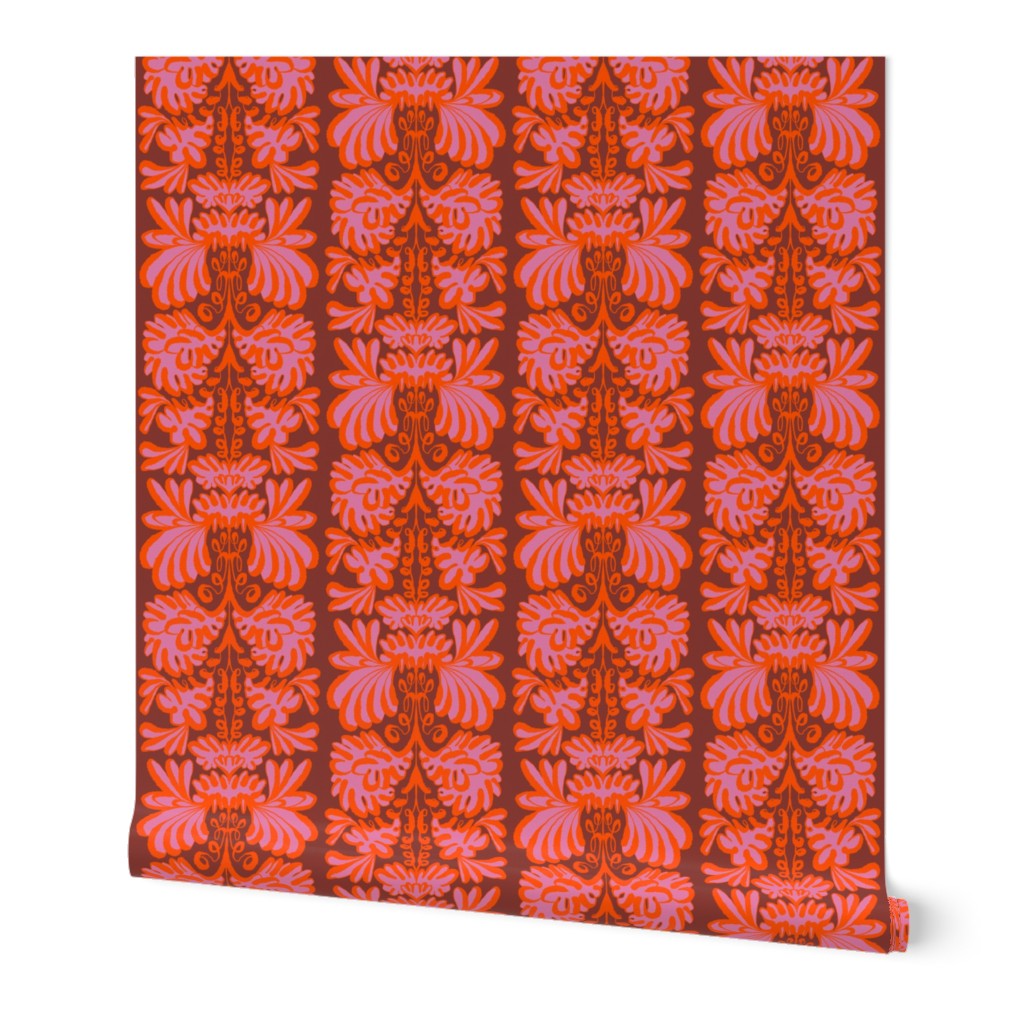 A roll of wallpaper featuring a vertical damask pattern in vibrant shades of red, orange, and pink, shown against a plain white background. Designed by artist Leila Simon Hayes.