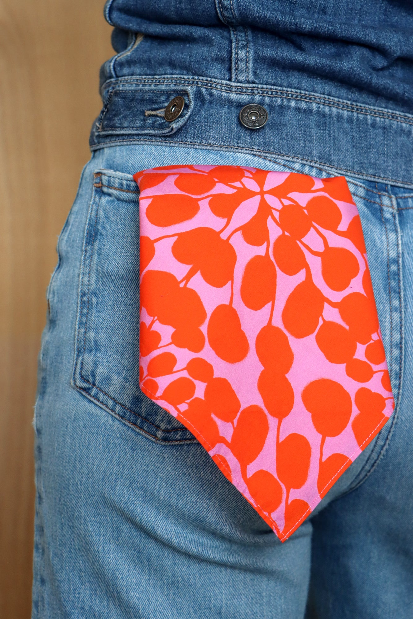 Person wearing a pink and orange patterned bandana in their jeans pocket. Designed by artist Leila Simon Hayes.